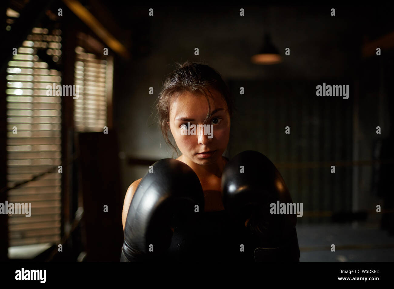 Dramatic portrait of young woman looking at camera with determination