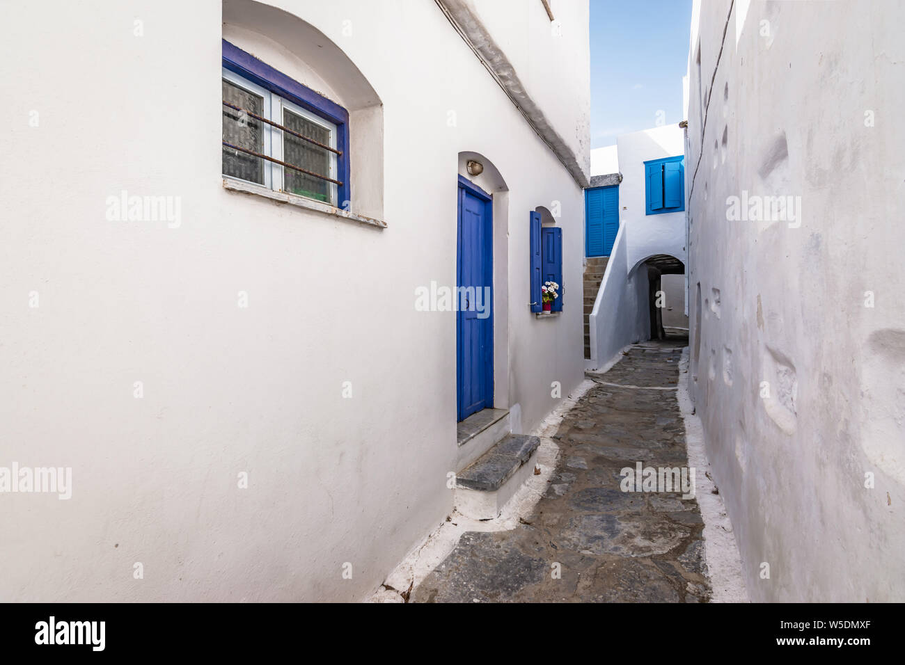 Narrow Street Between White Traditional Houses With Blue