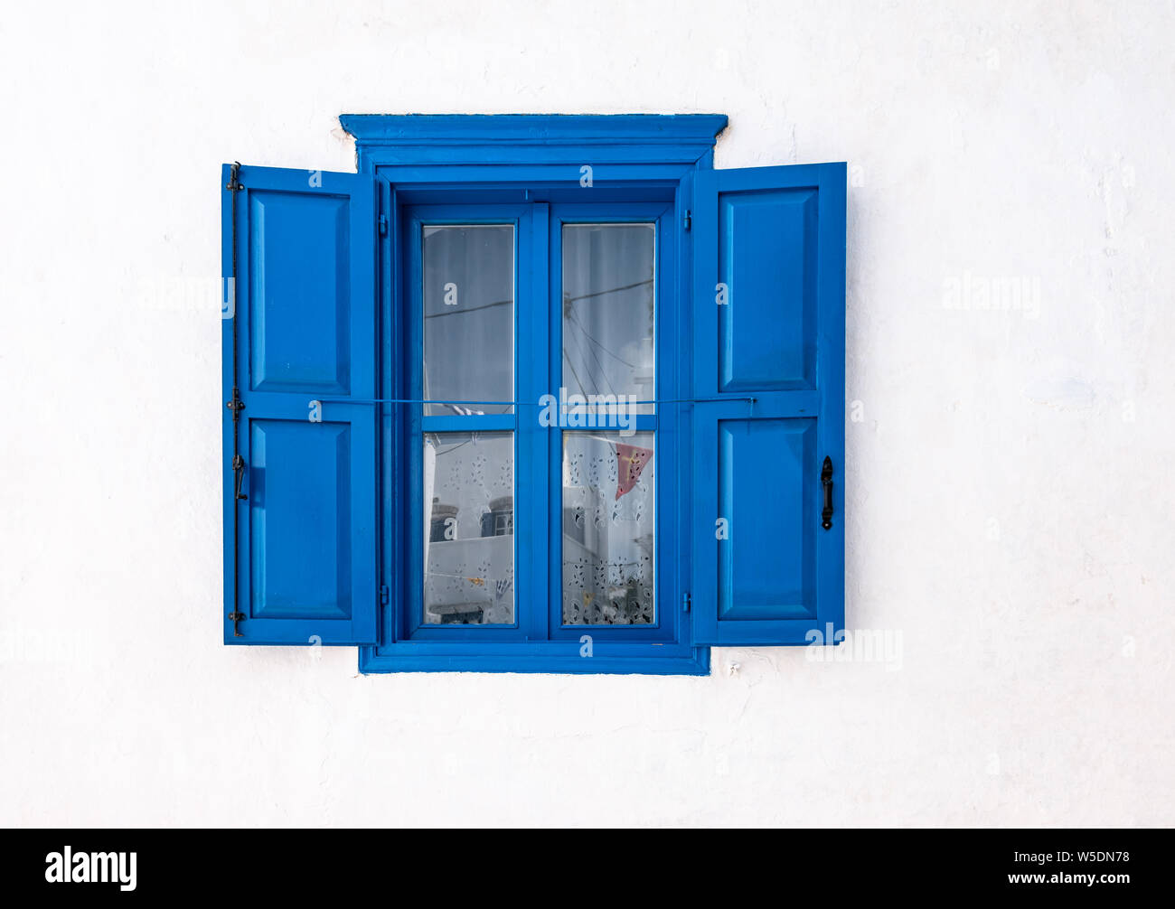Blue window with open shutters and white wall of greek house in Amorgos, Greece. Stock Photo