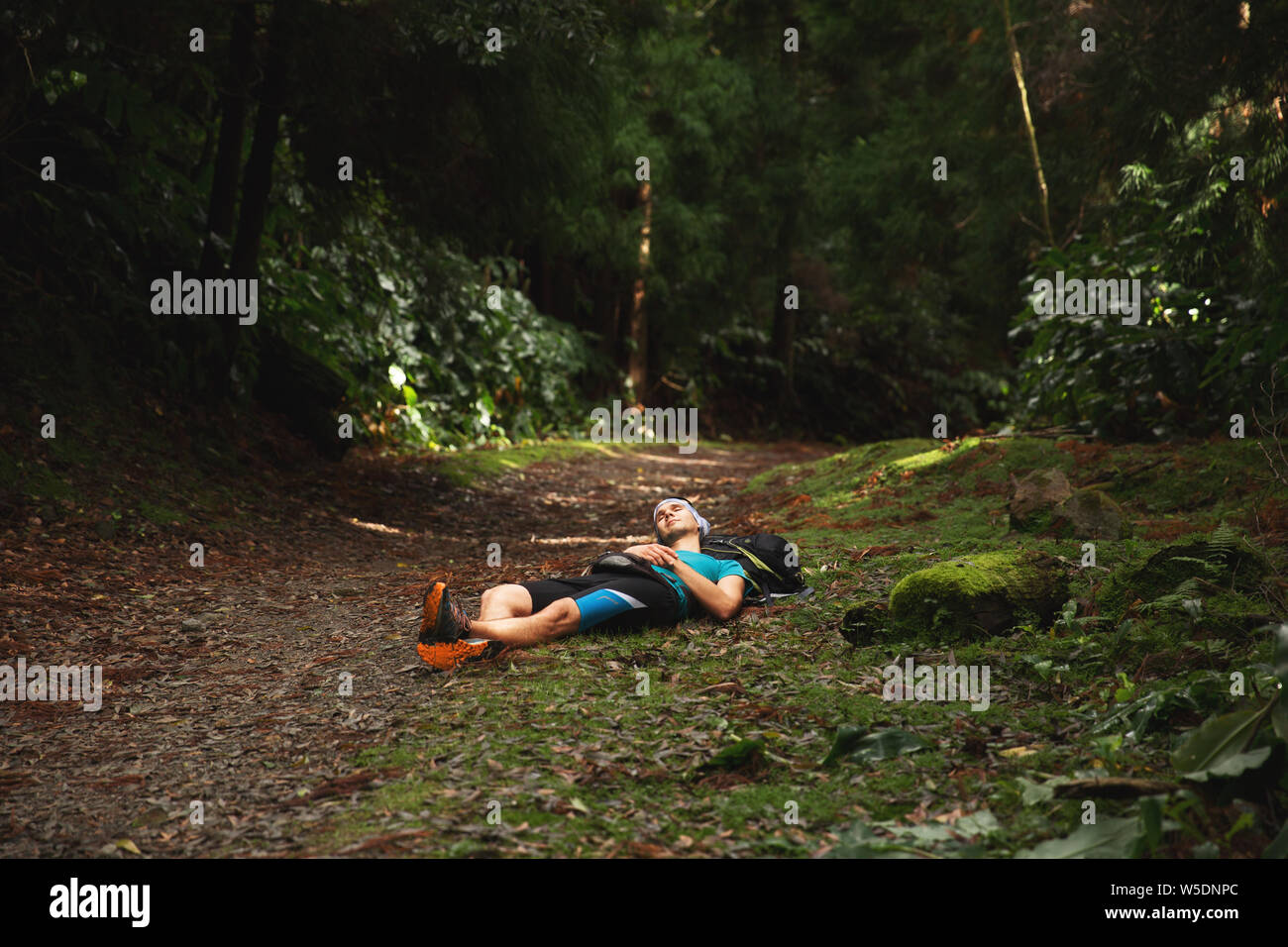 Restful young man lying down on ground in forest. Sao Miguel island, Azores Stock Photo