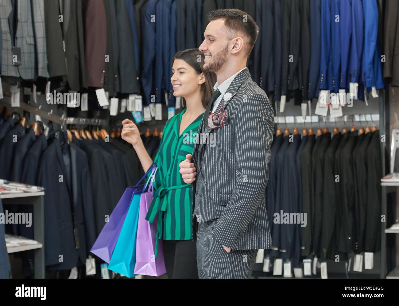 Happy man in stylish suit and white shirt and woman with many colorful