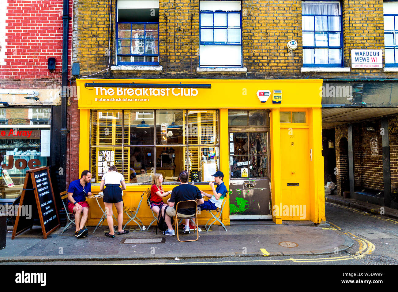 People sitting outside The Breakfast Club restaurant in D'Arblay Street, Soho, London, UK Stock Photo