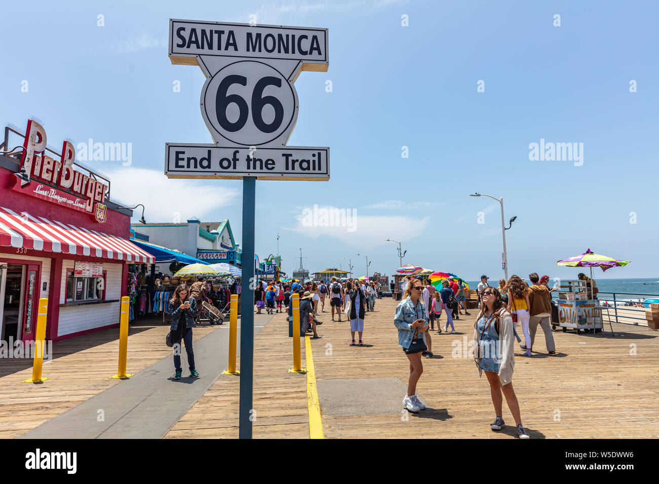 Los Angeles California USA. May 30, 2019. Santa Monica pier and Route 66 End of the trail, white color  sign. People walking at pier, blue sky backgro Stock Photo