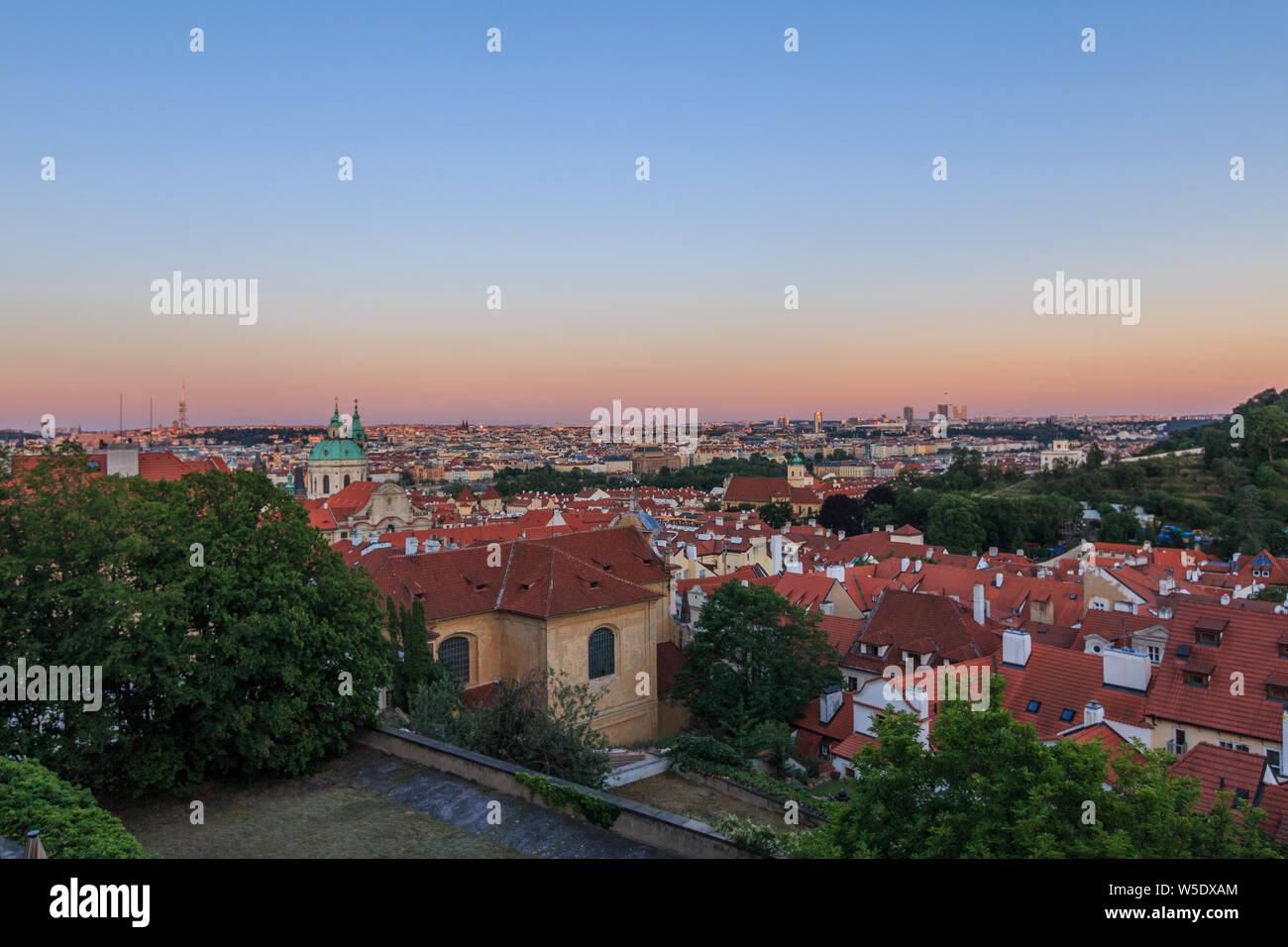 View over Prague in the evening. Red evening sun colors the horizon. Cityscape of Prague Castle above the roofs of the Lesser Town and Old Town distri Stock Photo