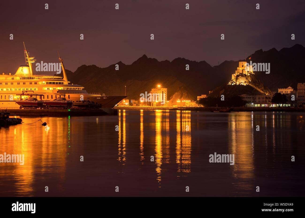 Beautiful view of the Muscat port of Oman with a lighted ship and background fort at night time. Stock Photo