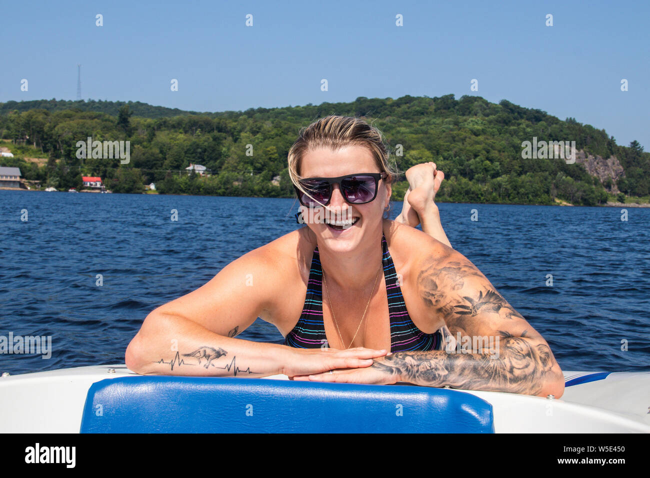Blond caucasian woman sunbathing on a boat deck on a lake at summer Stock Photo