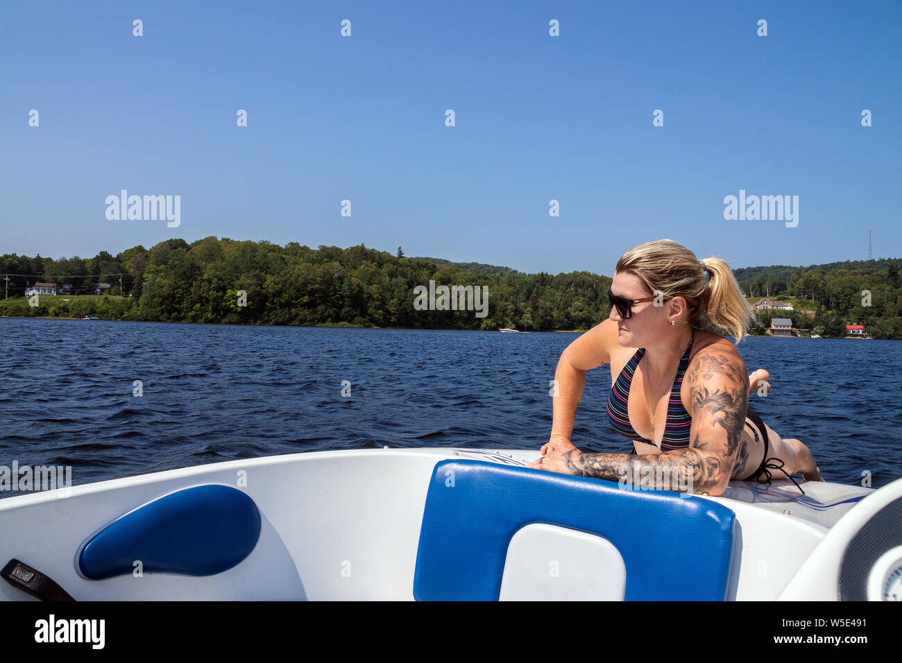 Blond caucasian woman sunbathing on a boat deck on a lake at summer Stock Photo