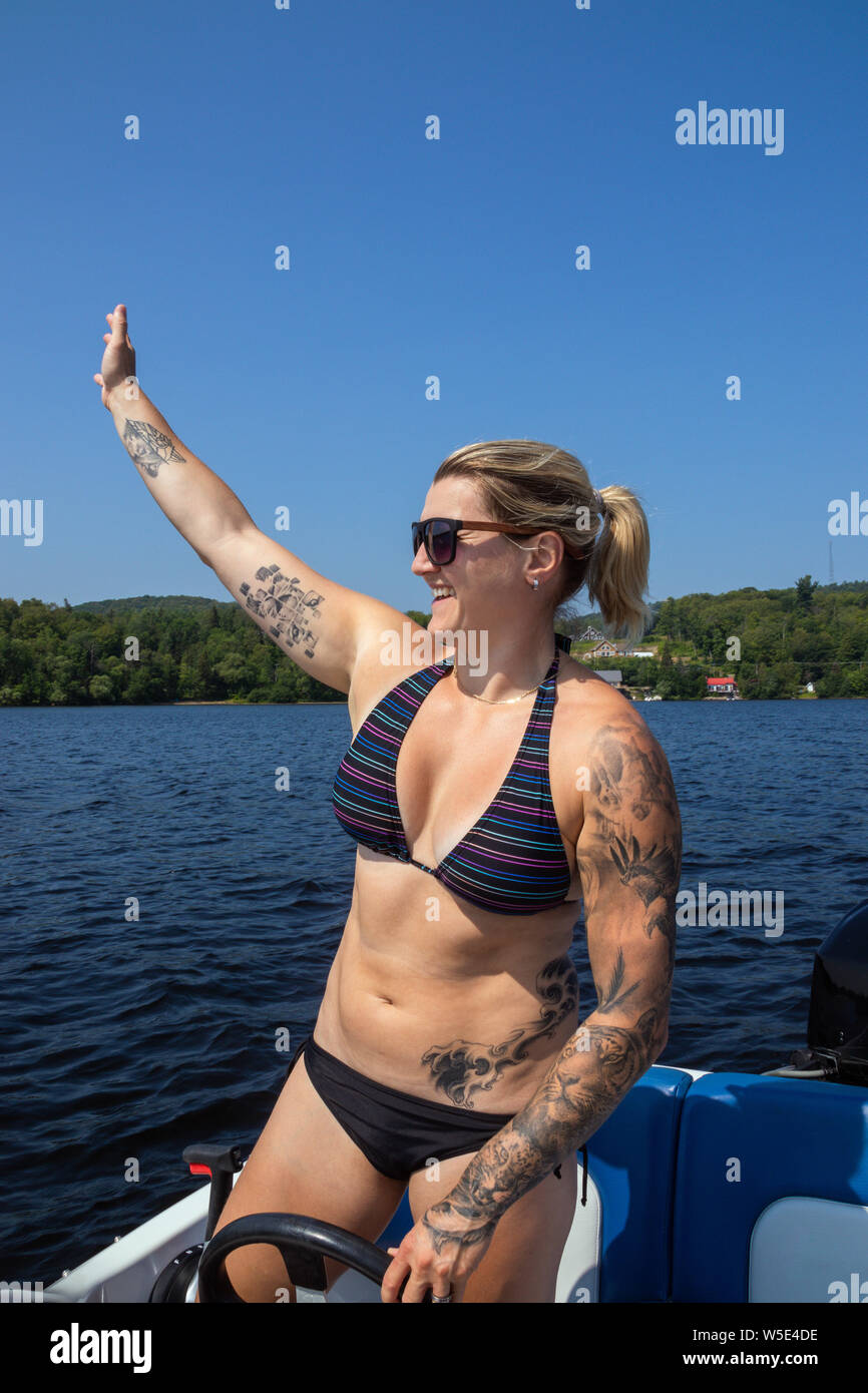 Blond caucasian woman driving a sport boat on a lake Stock Photo
