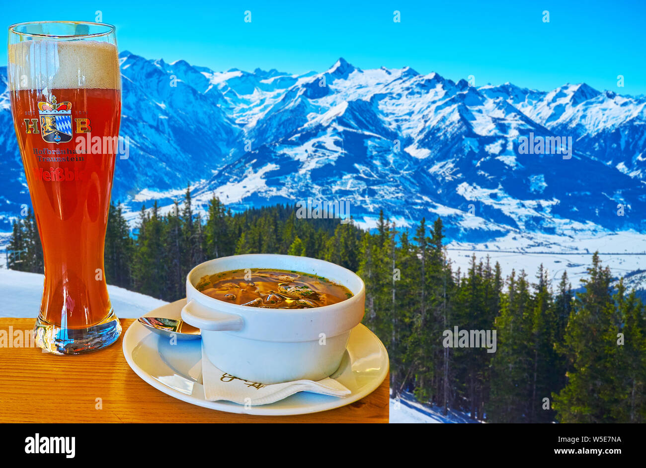 ZELL AM SEE, AUSTRIA - FEBRUARY 28, 2019: Enjoy the dinner with sliced pancake soup and beer in cafe, located on Schmitten mountain slope and overlook Stock Photo