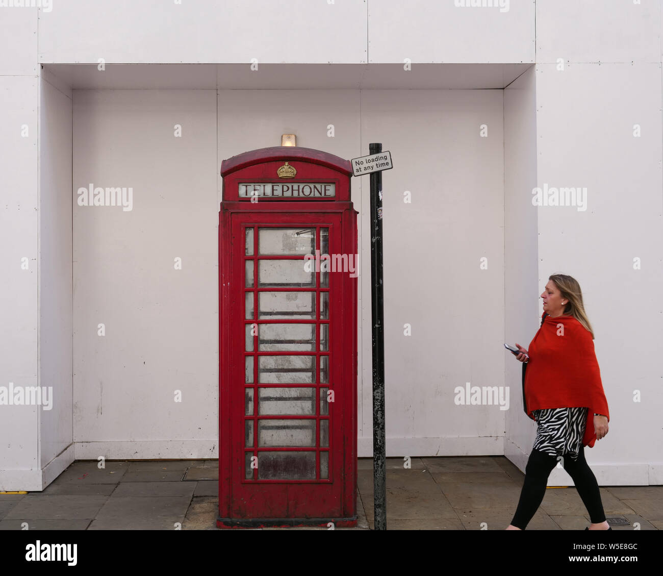 Lady in red with a mobile phone in her hand, approaches a classic