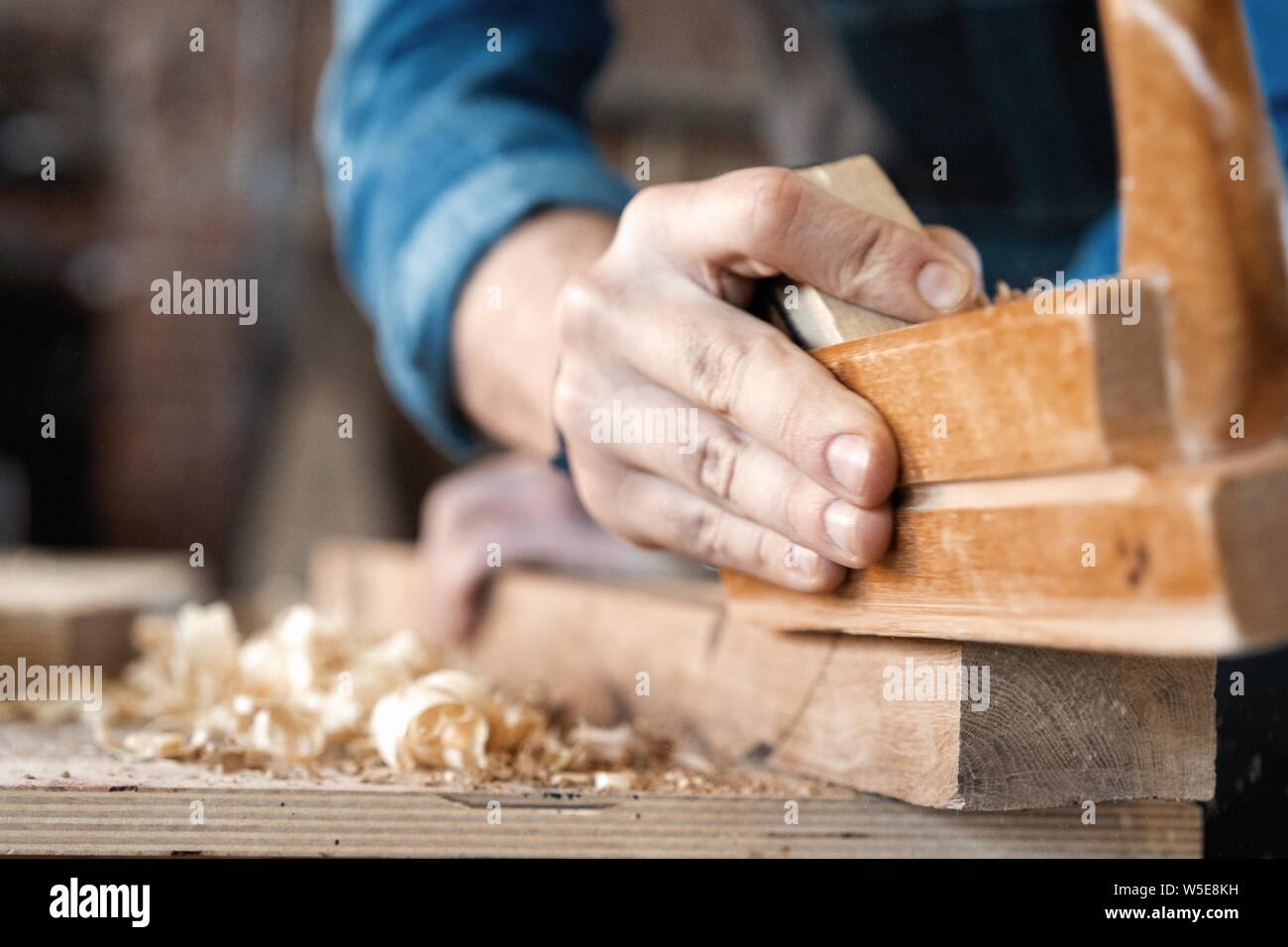 carpenter working with plane on wooden background. Stock Photo