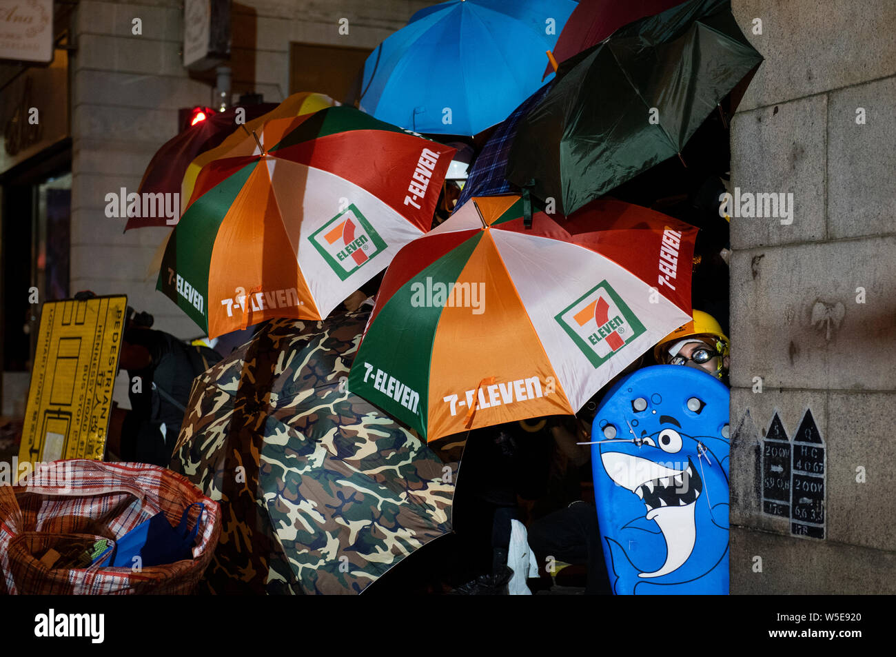 Protesters take cover behind an umbrellas during the clashes. .Tens of thousands of pro-democracy protesters marched in central Hong Kong in yet another round of anti government demonstration. Riot police has used tear gas and rubber bullets against protesters despite the fact that the police force has been widely commended by the public for their disproportionate use of force against the protesters in past demonstrations triggered by the controversial extradition bill put forward by the Hong Kong government. Stock Photo