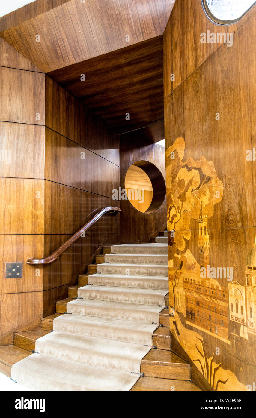 Stairs from the entrance hall of the art deco mansion Eltham Palace and wooden walls featuring figurative marquetry, Eltham, UK Stock Photo