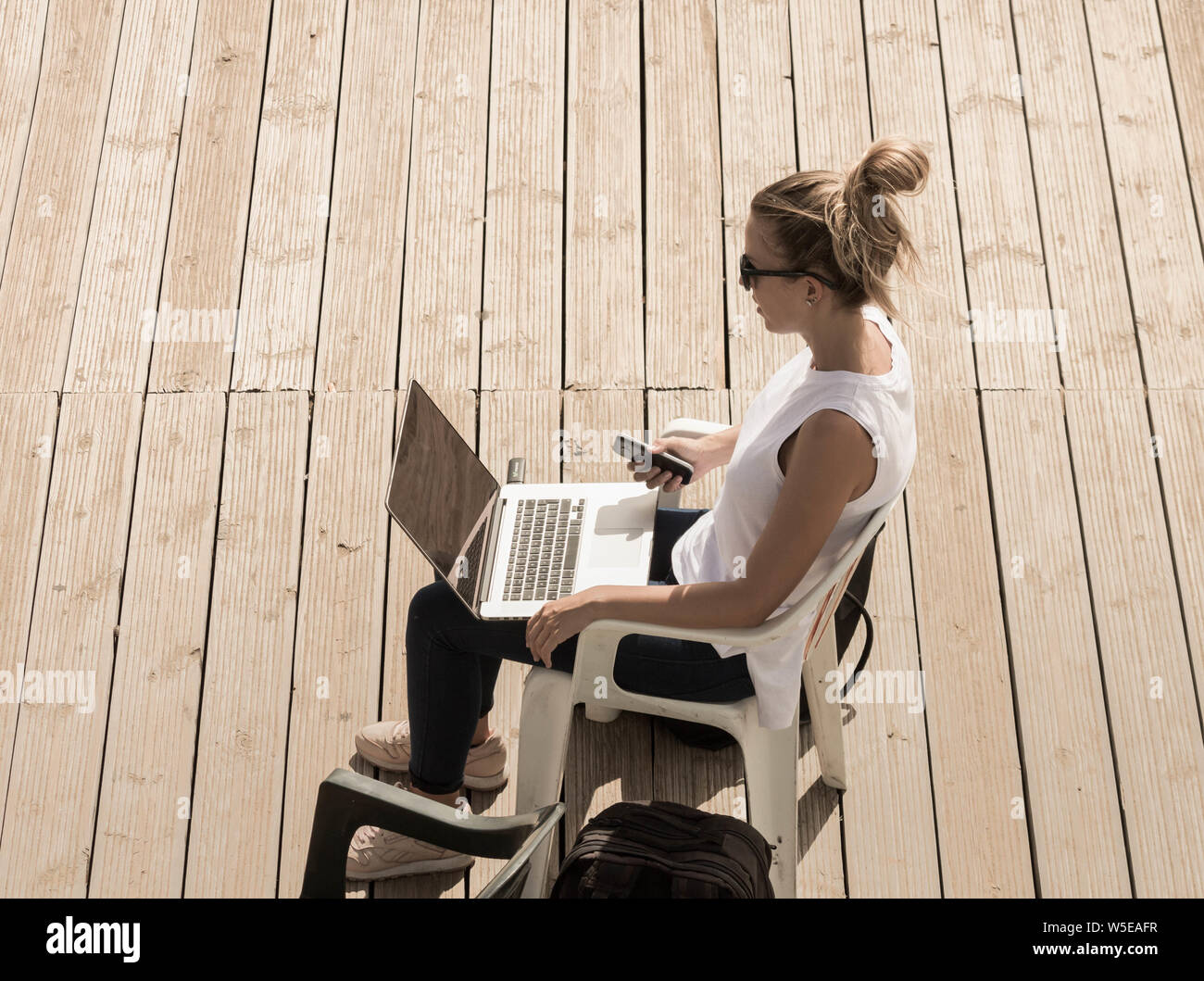 Woman using laptop on beach boardwalk. Stock Photo