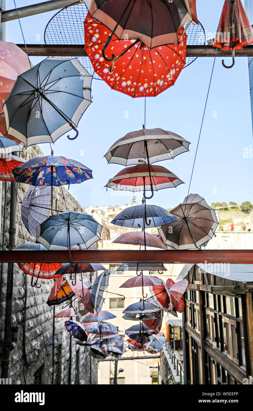 Umbrellas hang from wires in the sky over a narrow passageway in Amman, Jordan. Stock Photo