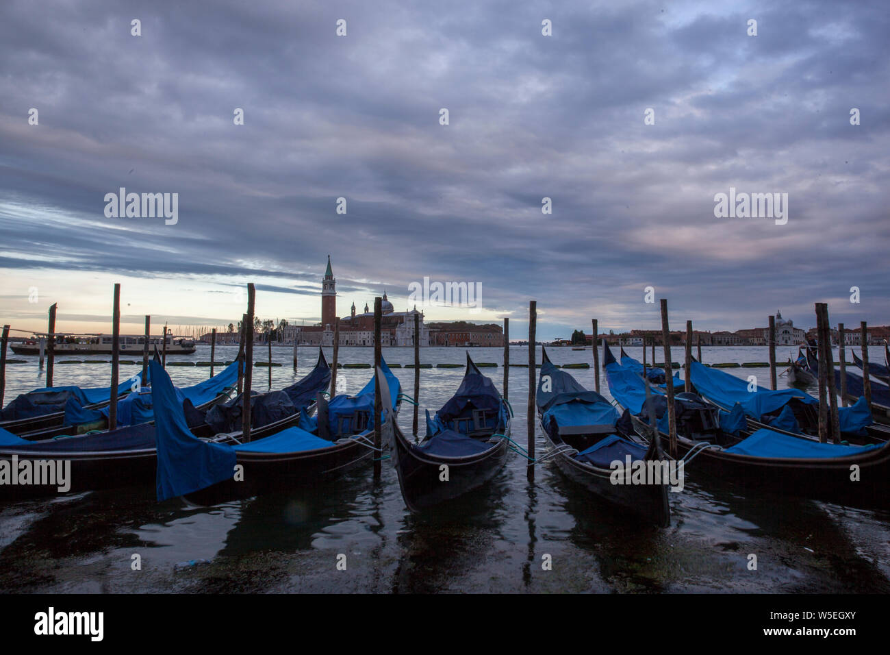 Gondolas in Venice at dusk/twilight, taken on the shoreline besides the Piazza San Marco / St Marks Square.Image was taken during a dramatic sunset Stock Photo