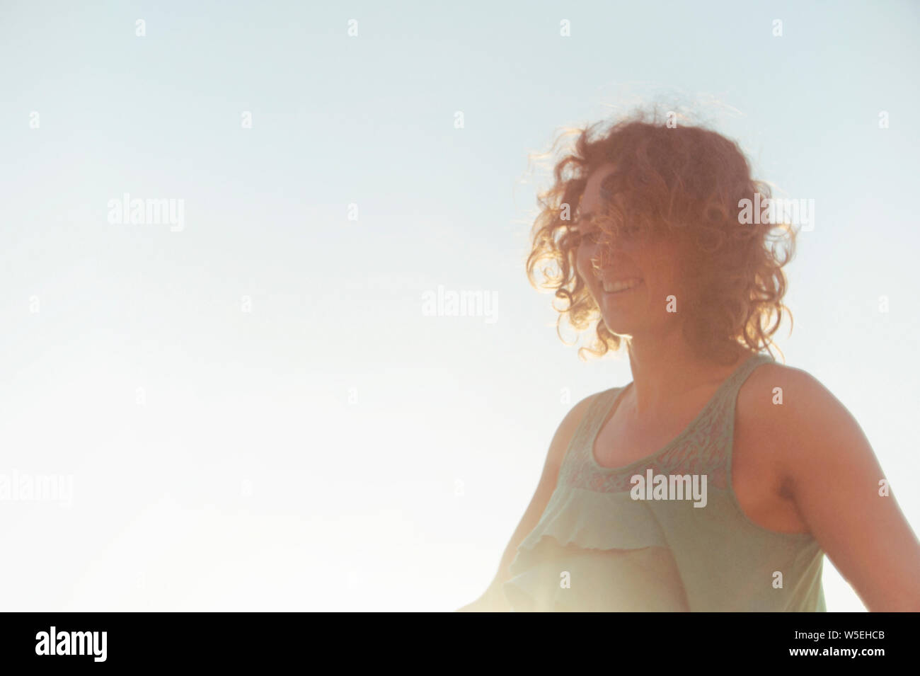 Happy woman with wind blown beach hair with a big empty sky background. Stock Photo