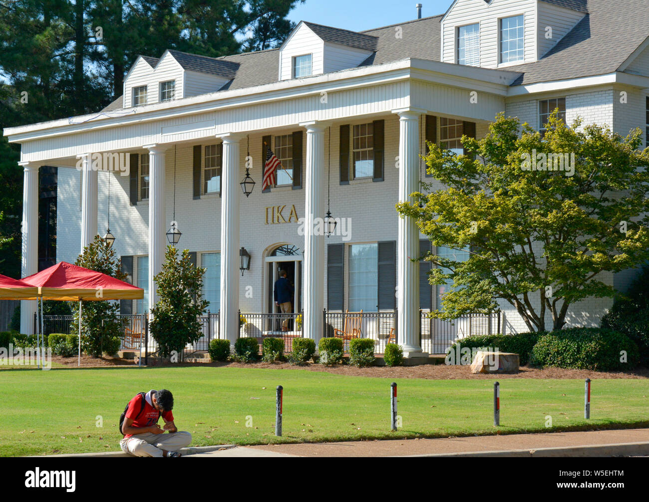 A pledge enters the Pi Kappa Alpha Fraternity Building on the campus of Ole Miss, while another sits outside at the University of Mississippi, Oxford Stock Photo