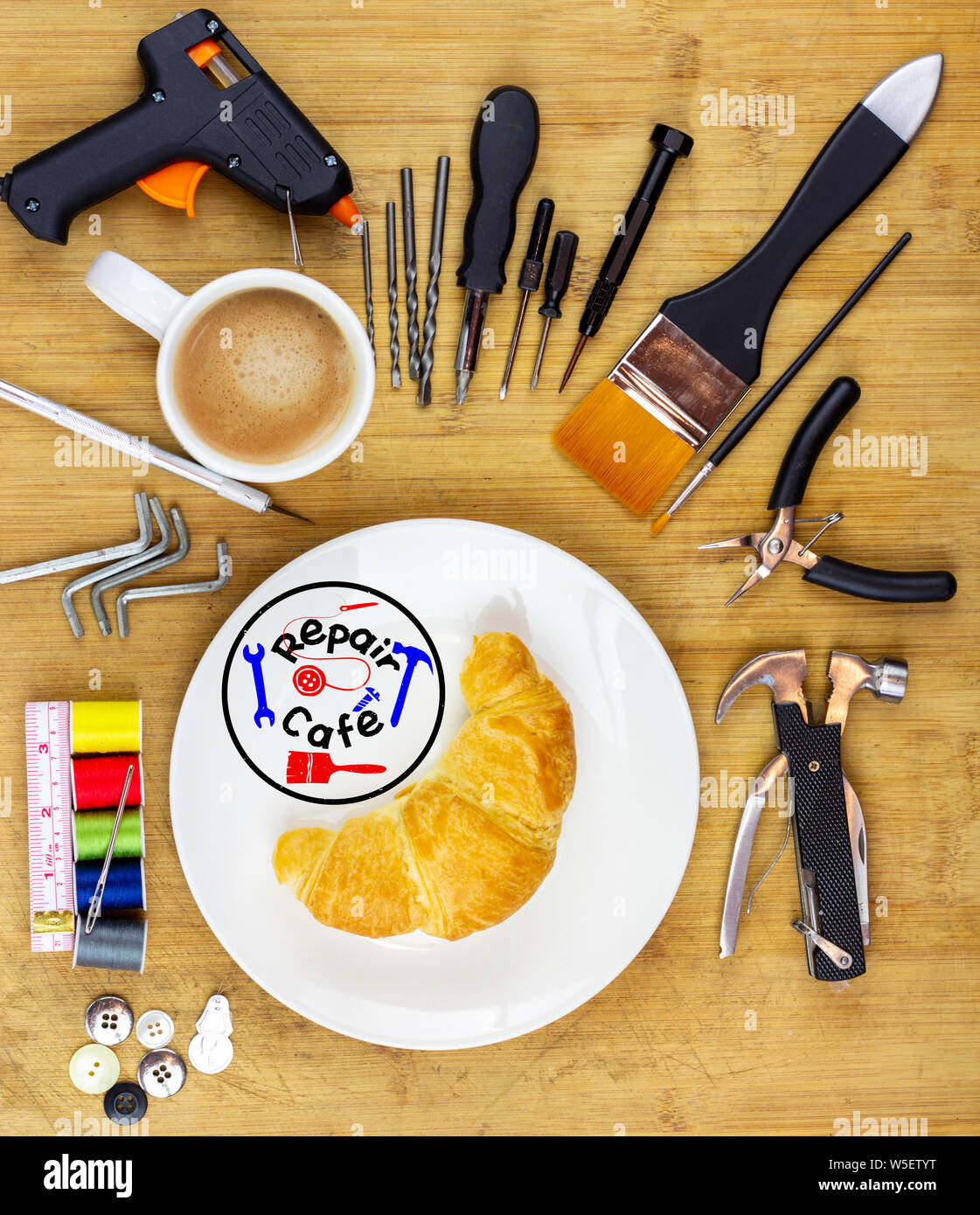concept illustration for Repair Cafe, plate surrounded by repair tools on wooden work table top, consumer activism to repair household items to reduce Stock Photo