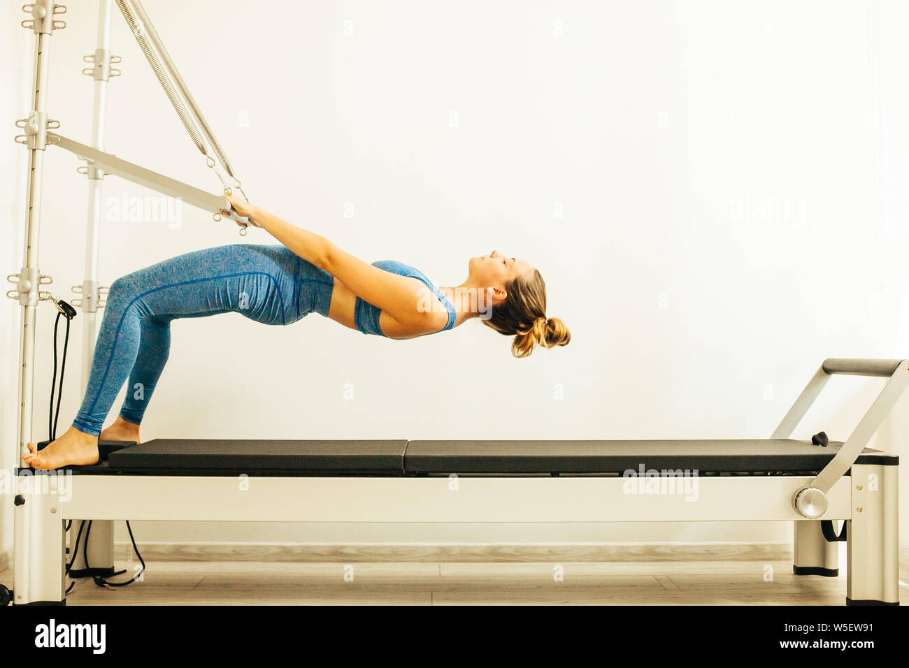 Woman performing Pilates exercise using a Cadillac or Trapeze