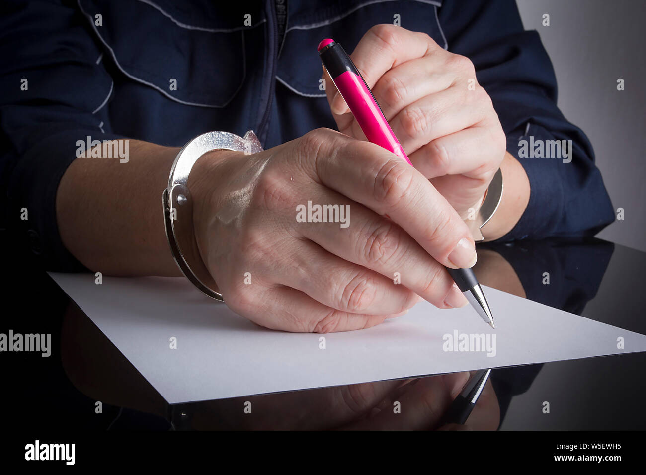 Female hands handcuffed with a pen and a sheet of white paper Stock Photo