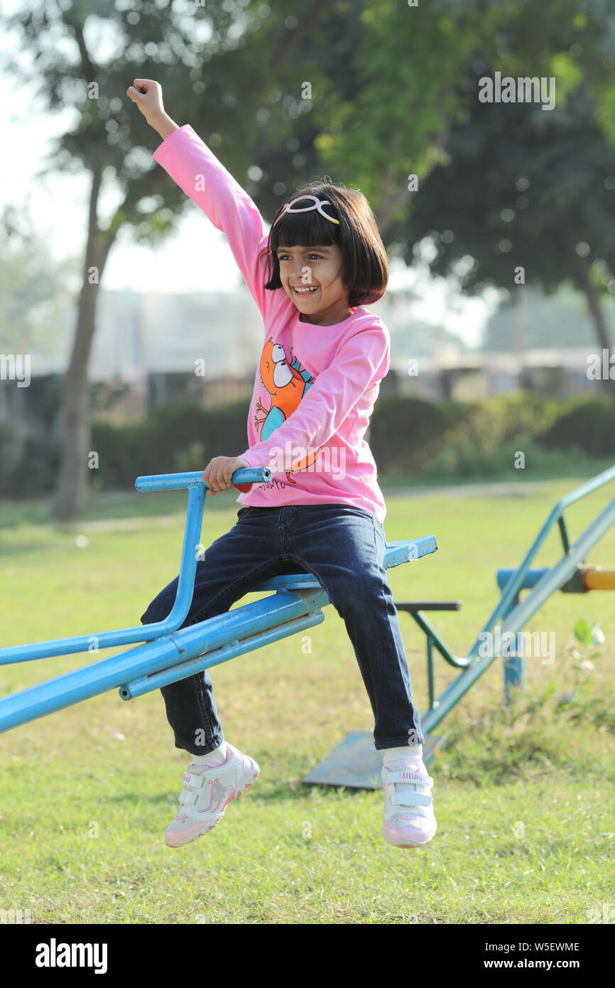 Girl sitting on seesaw in park Stock Photo Alamy