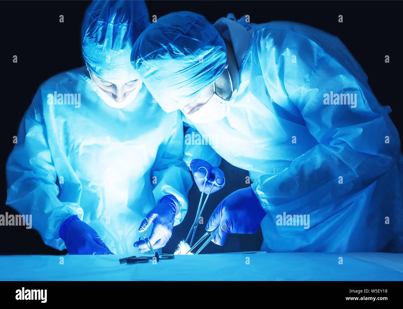 Two surgeons, a man and a woman, perform surgery to remove prostate adenoma and varicocele, fibroadenoma, operating theater Stock Photo
