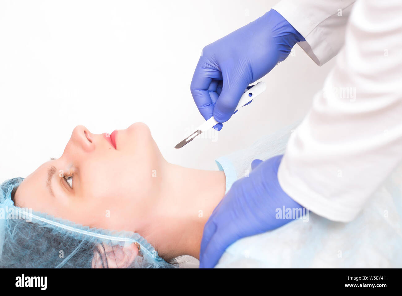 Doctor holds a scalpel against the background of a girl who has problems with the endocrine system and the thyroid gland, copy space, endocrinology Stock Photo