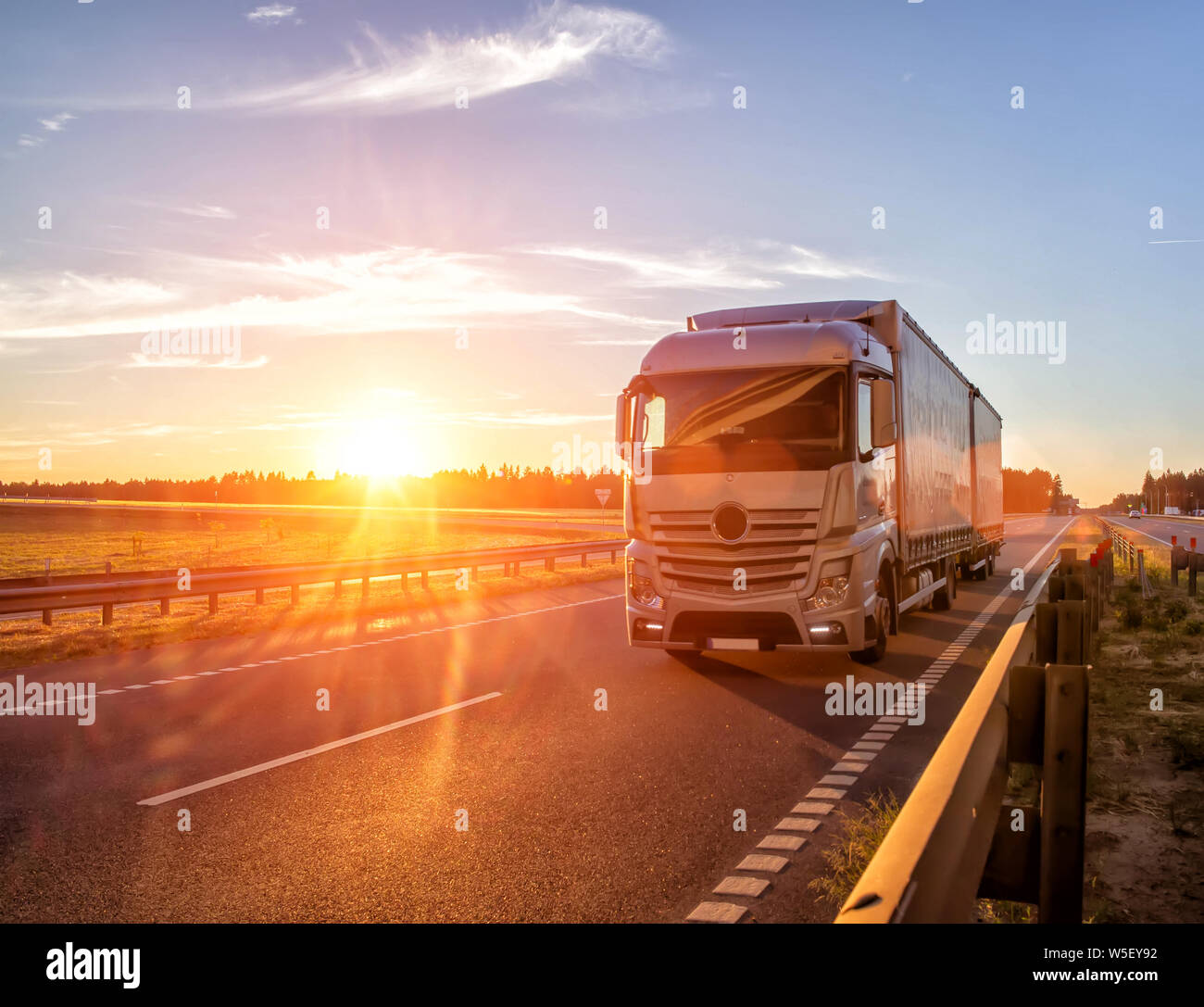 Modern wagon truck transports cargo against the backdrop of a sunset. The concept of truck