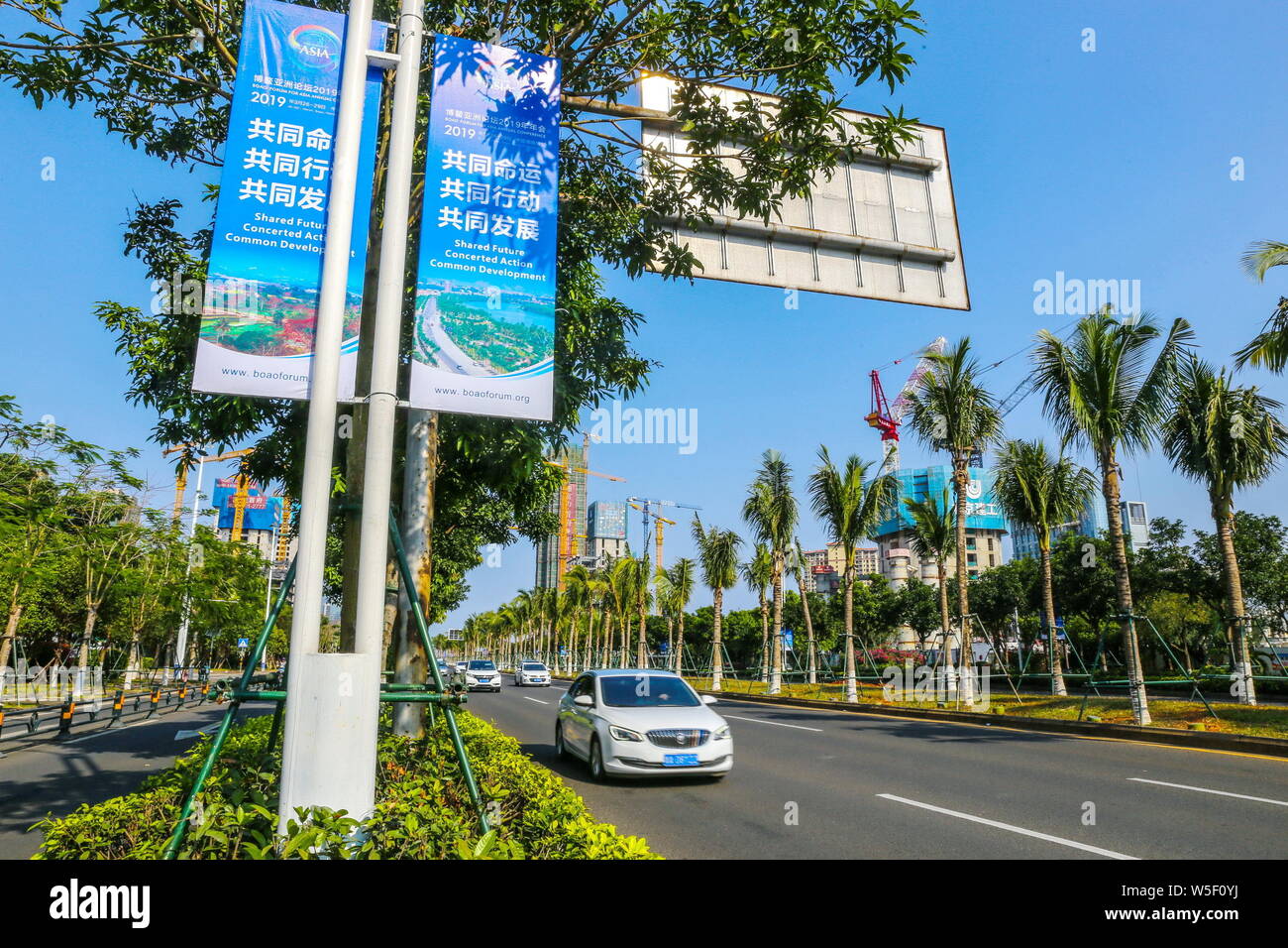 Cars drive past banners for the Boao Forum for Asia Annual Conference 2019 on lampposts in Haikou city, south China's Hainan province, 20 March 2019. Stock Photo