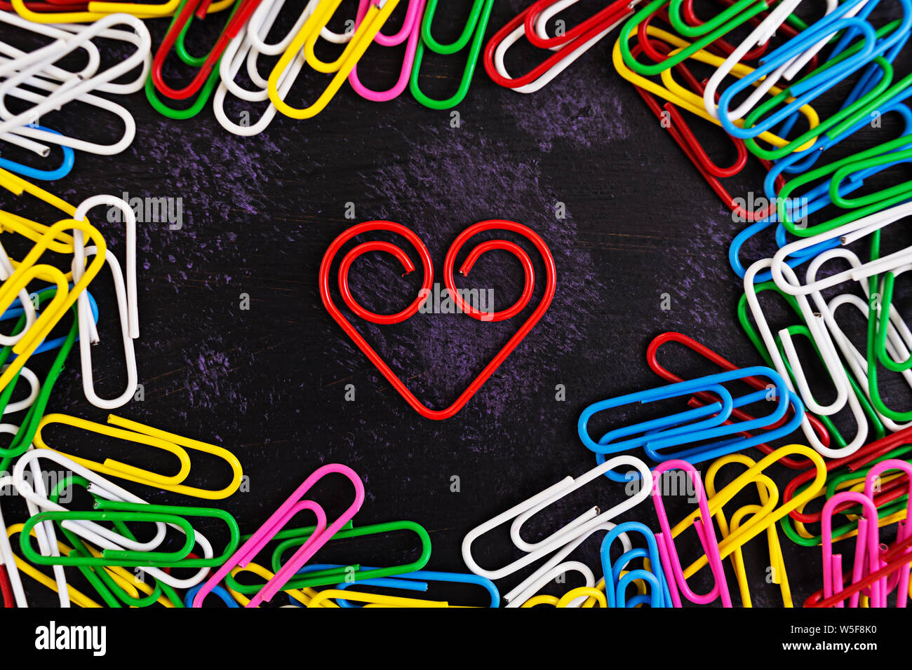 Colored paper clips isolated on dark background Stock Photo