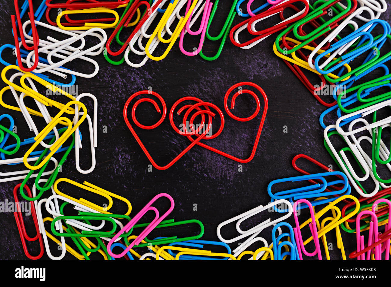 Colored paper clips isolated on dark background Stock Photo