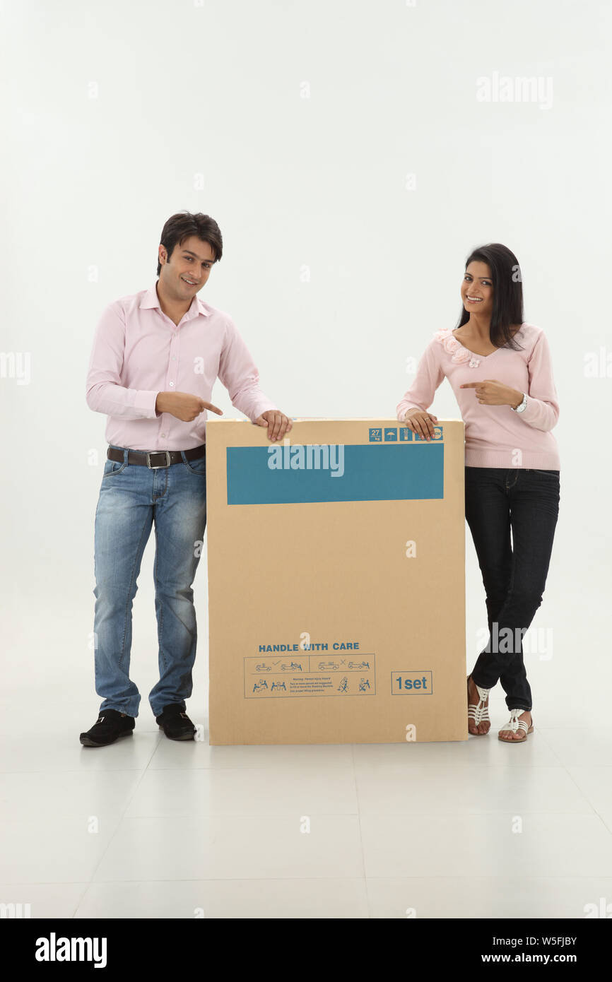 Couple showing a cardboard box and smiling Stock Photo - Alamy