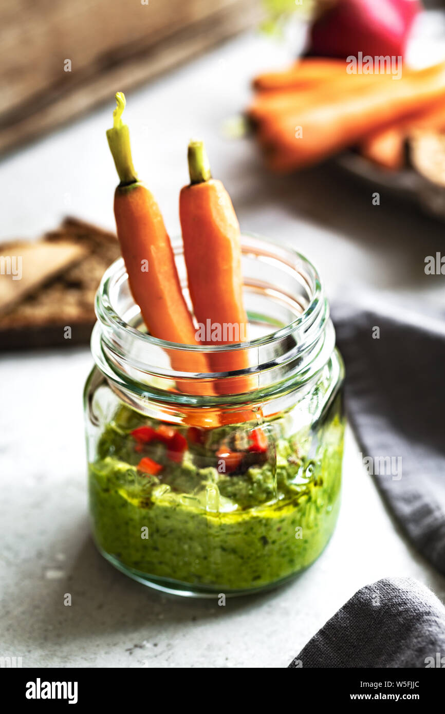Spinach Hummus in a glass jar by baby Carrot and Rye bread Stock Photo