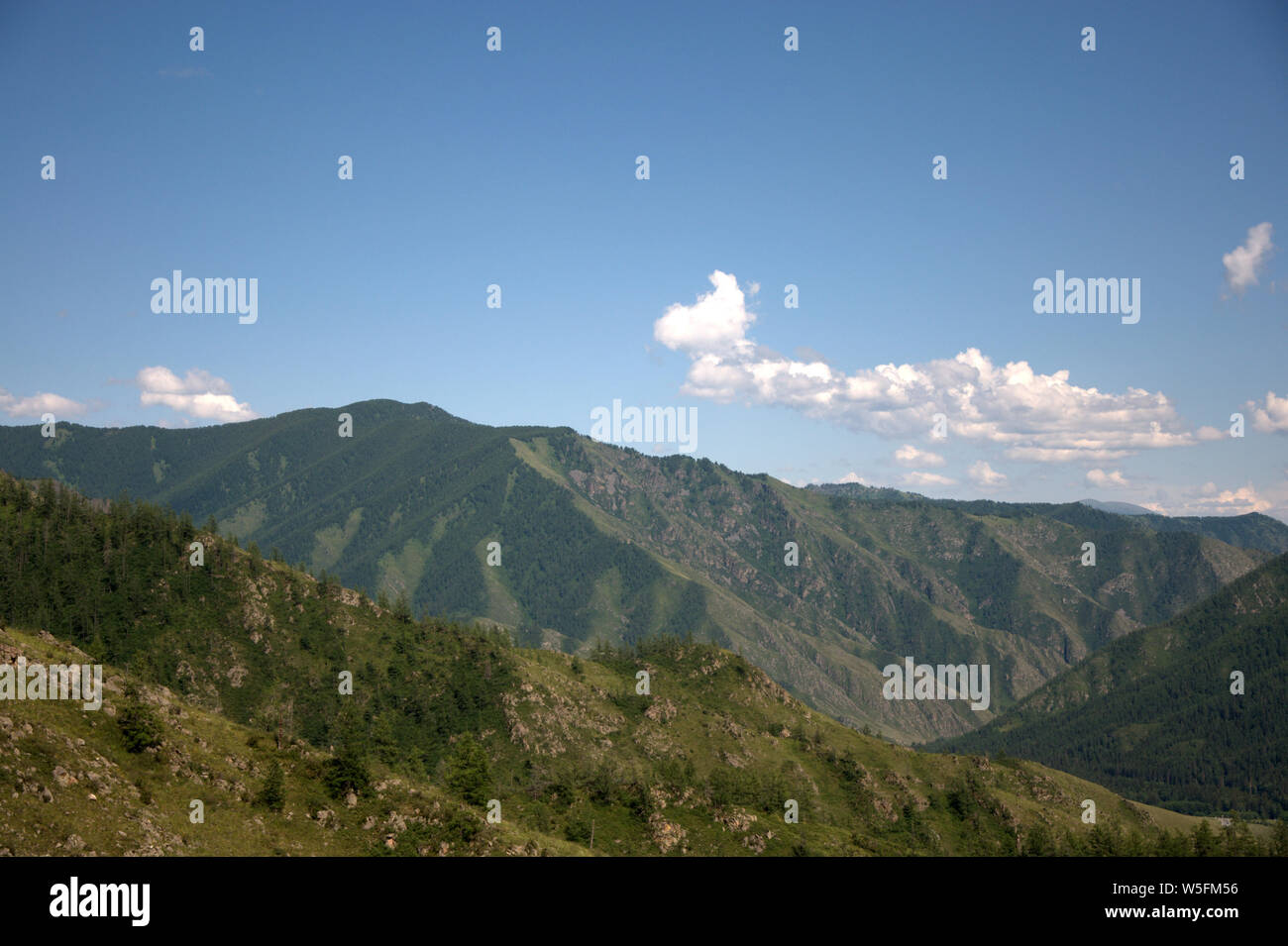 White fluffy clouds above a fertile green valley surrounded by ...