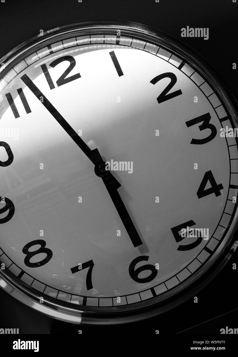The dial of the wall clock shows almost 6 pm. The end of the working day. Stock Photo