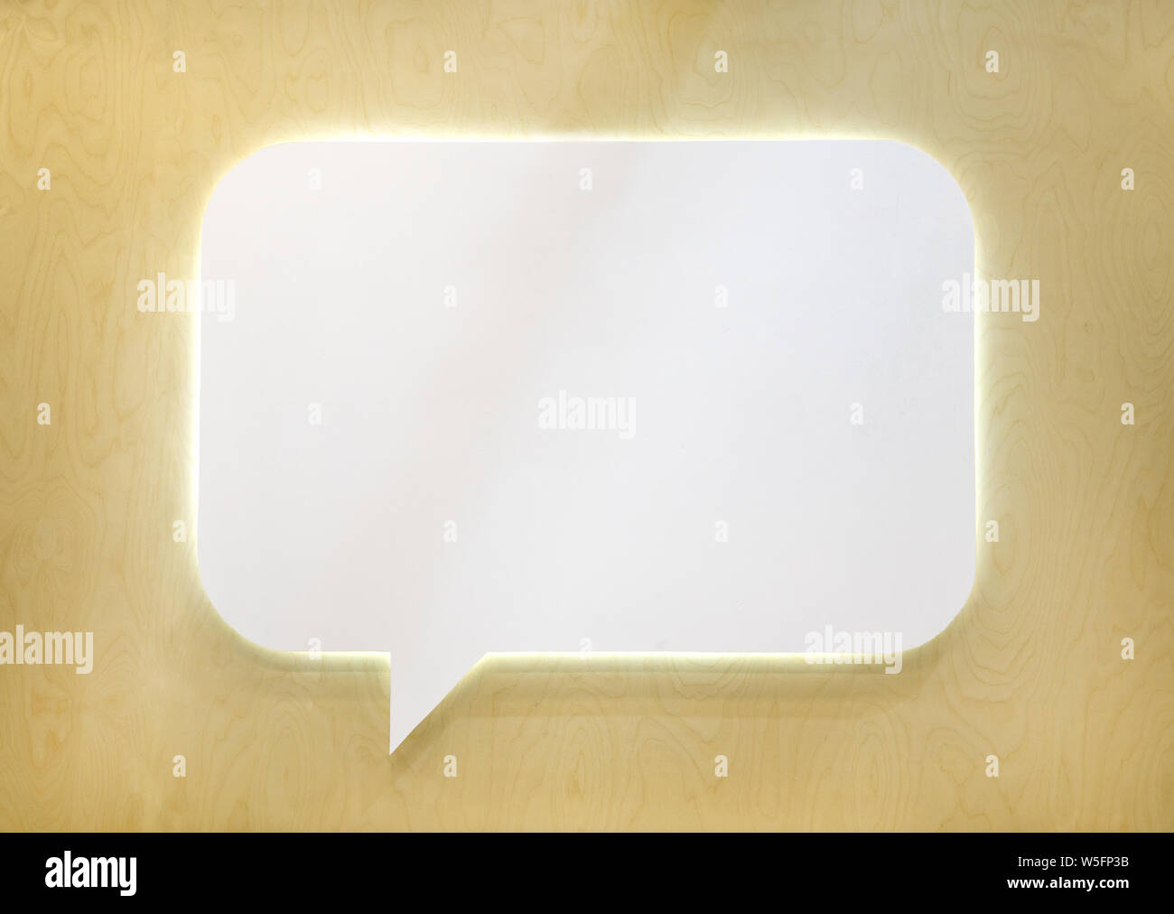 Empty white speech bubble on wooden wall. Stock Photo