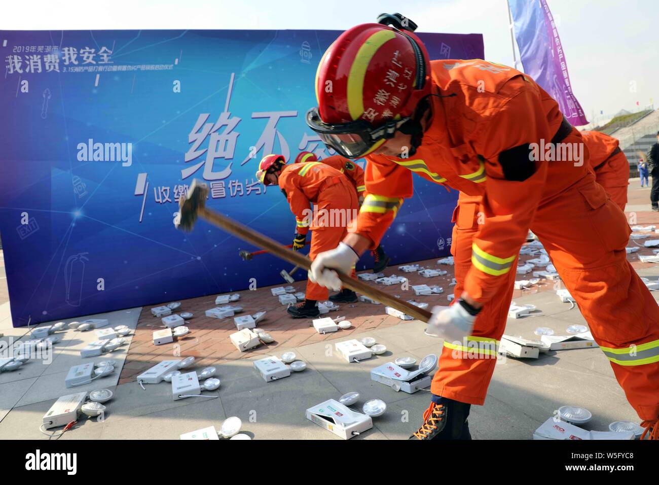 Chinese firefighters smash counterfeits of fire extinguishers on the World Consumer Rights Day, often referred to as '315' in China, in Changde city, Stock Photo