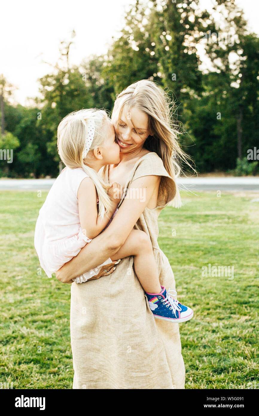 Young mother lifting and holding her happy daughter in her arms both smiling Stock Photo