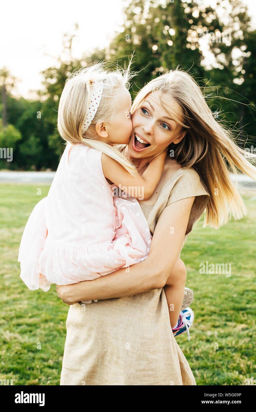 Young mother lifting and holding her happy daughter in her arms both smiling Stock Photo