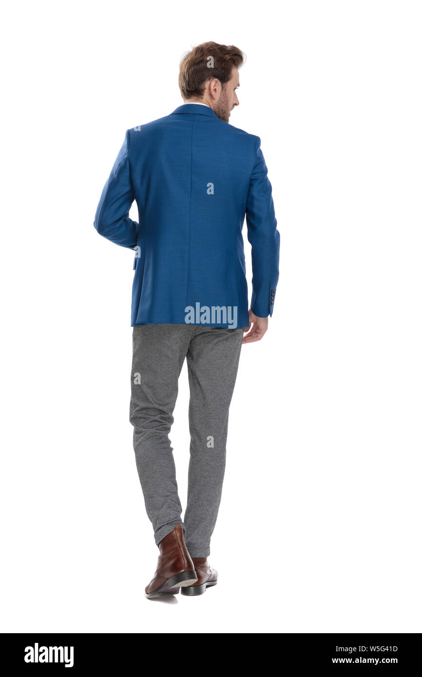 Back view of a confident casual man walking and looking to the side ...