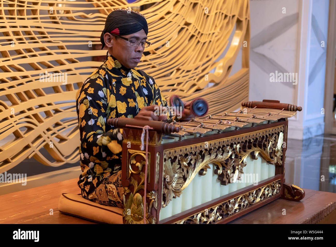 A Javanese man playing slenthem, a Javanese traditional music instrument part of gamelan orchestra. Stock Photo