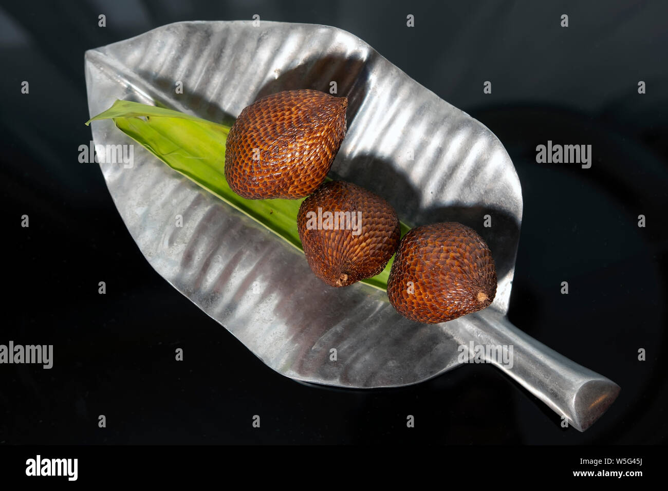 Snakefruit on a leaf shape silver plate with dark background Stock Photo