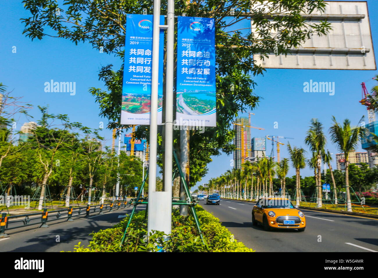 Cars drive past banners for the Boao Forum for Asia Annual Conference 2019 on lampposts in Haikou city, south China's Hainan province, 20 March 2019. Stock Photo