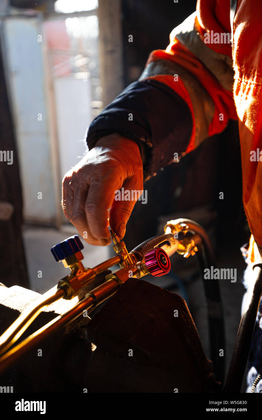 Man repairing and cleaning cutting torch in his workshop, selective focus. Stock Photo