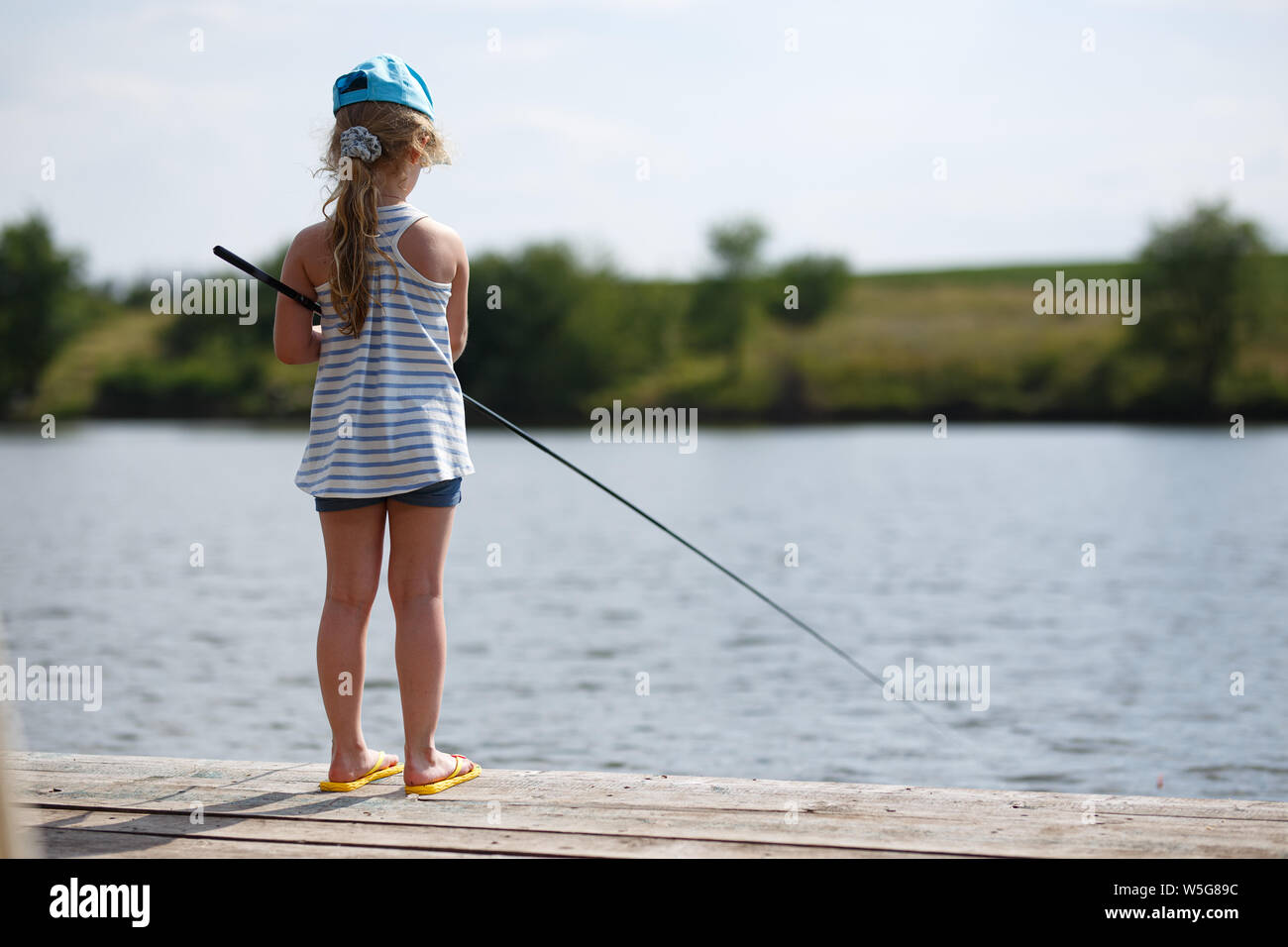 Маленький догони. Маленькая девочка рыбачит. Девочка поймала рыбу. Девушка с удочкой на пирсе. Девочки маленькие на рыбалке ловят рыбу.