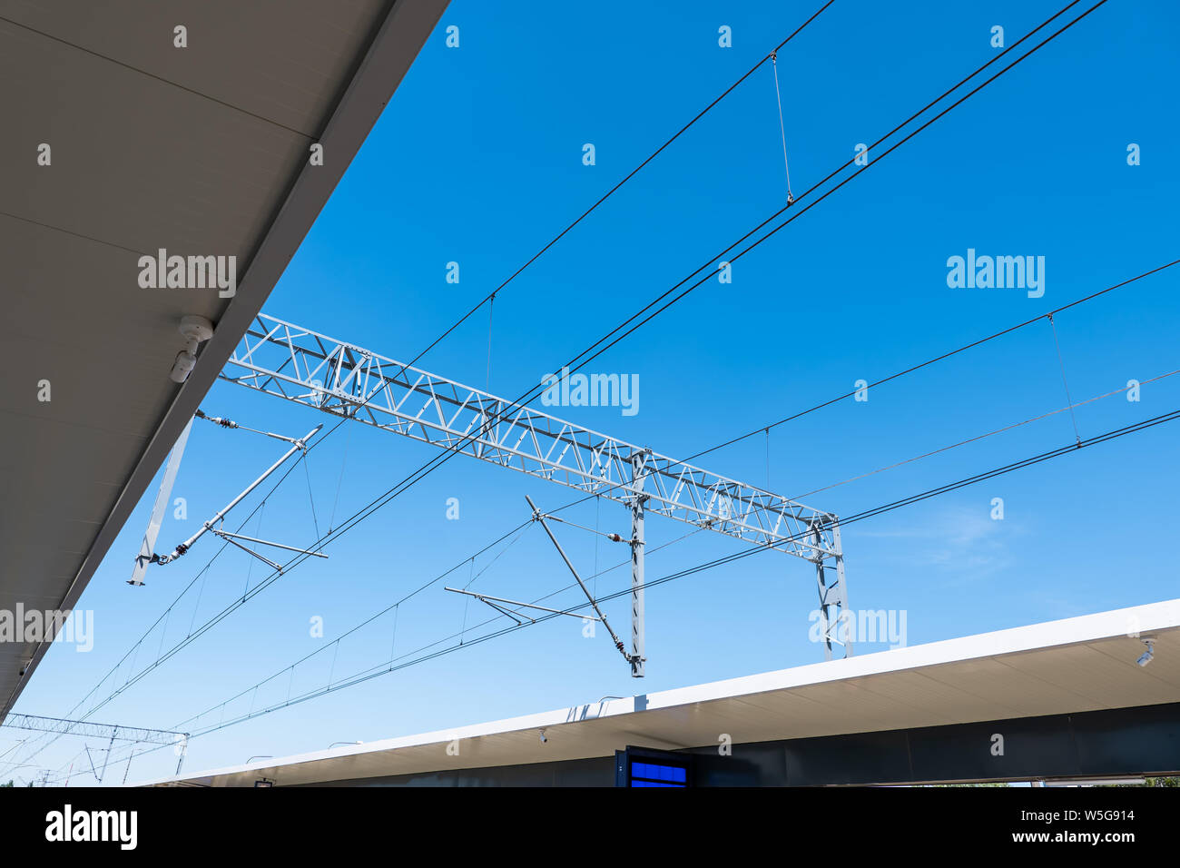Railway electric traction above the station against a blue sky. Stock Photo