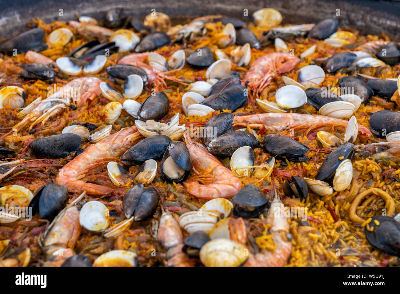 Paella de Marisco seafood with Hispanic rice, prawns, mussels, clams on large pan. Stock Photo