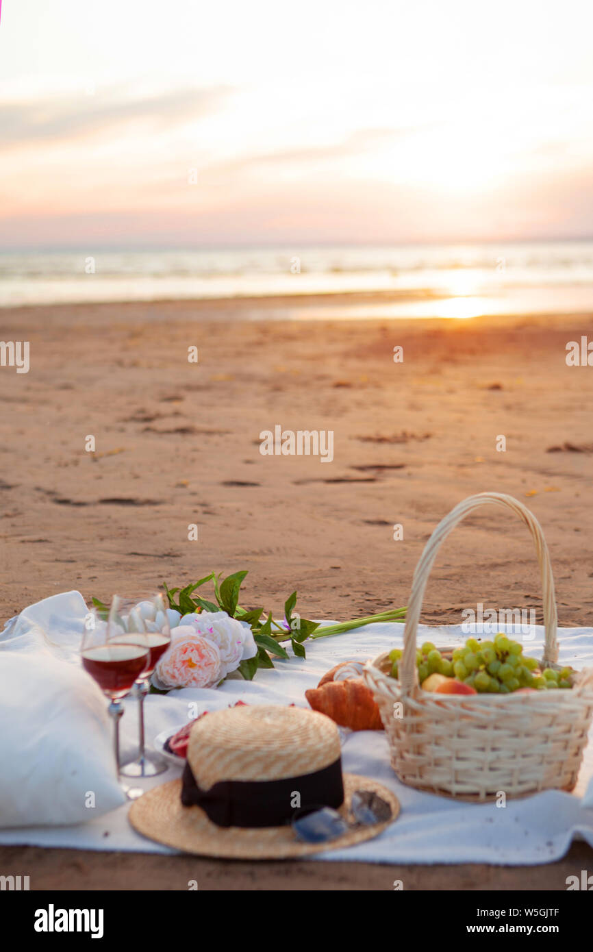 Picnic in the rays of the setting sun on the sand. On the plaid lies a