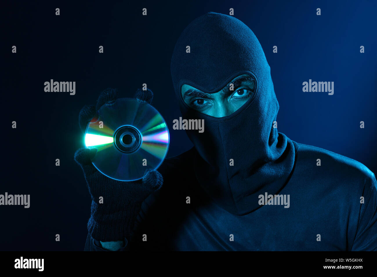 Hacker holding a pirated compact disc Stock Photo
